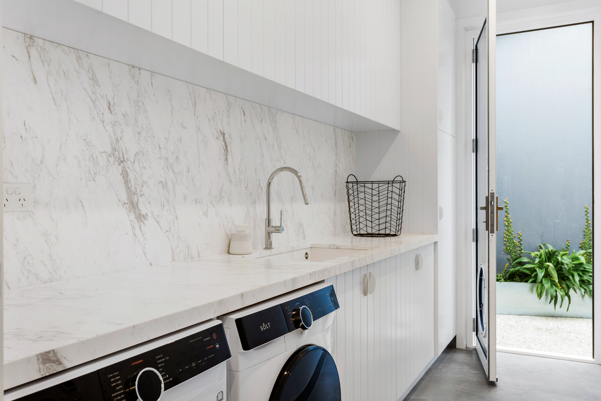 Marble laundry with white shiplap cabinetry